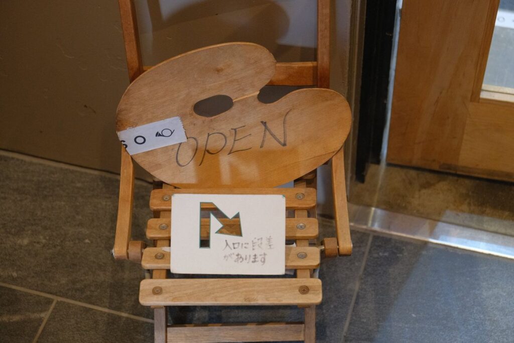 팔레트 모양의 OPEN 간판이 놓인 의자